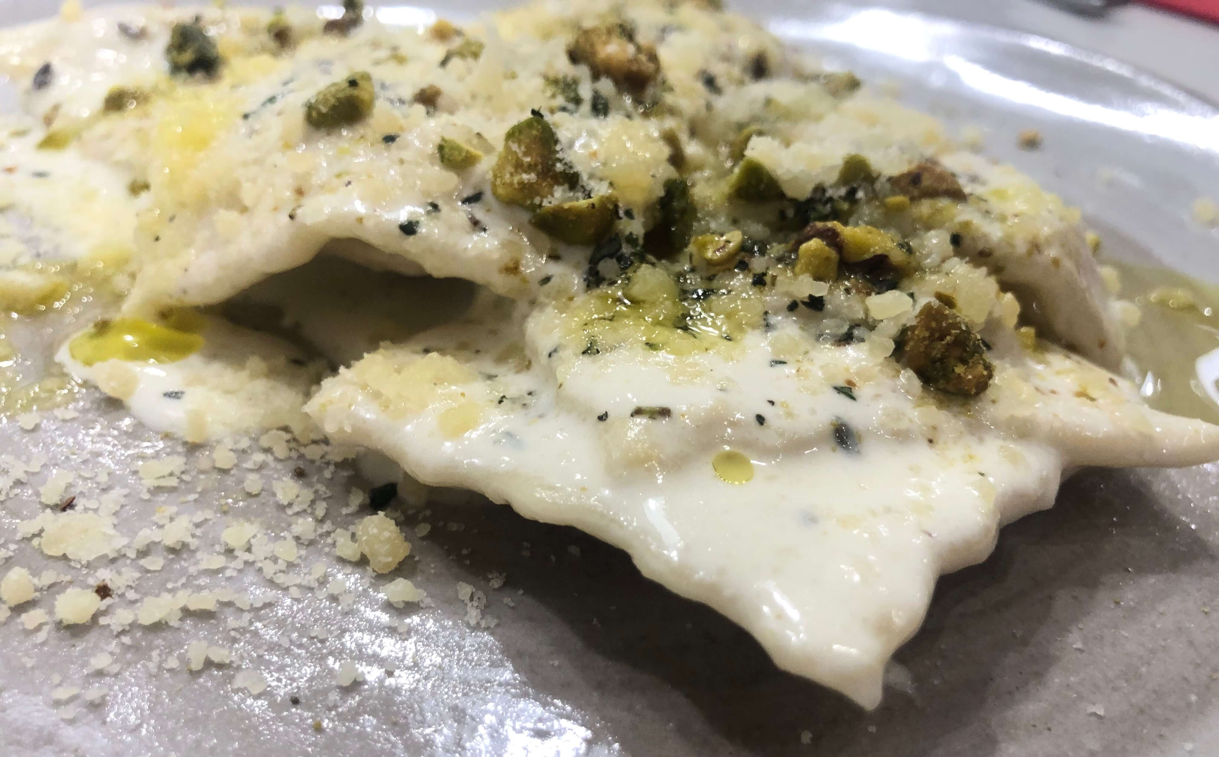 Signature Figue Ravioli. Goat cheese, dried figs, herbs, and lemon served with a creamy thyme and pistachio sauce.
